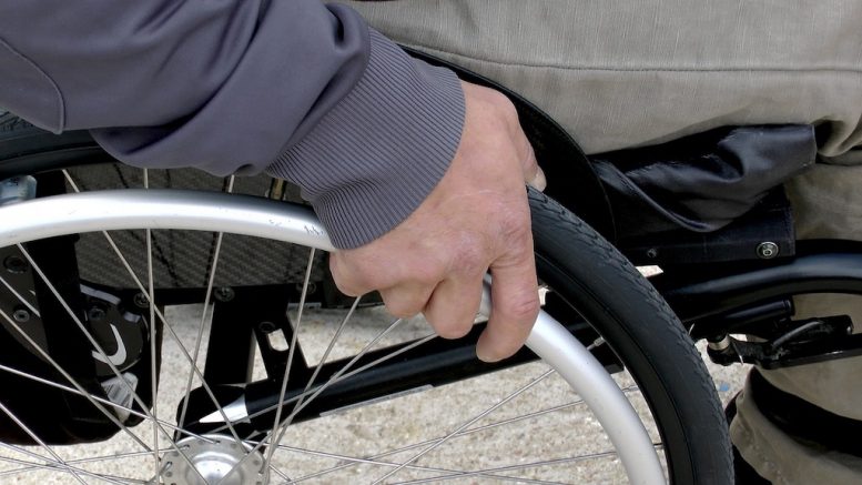 Main sur une roue d'une chaise roulante