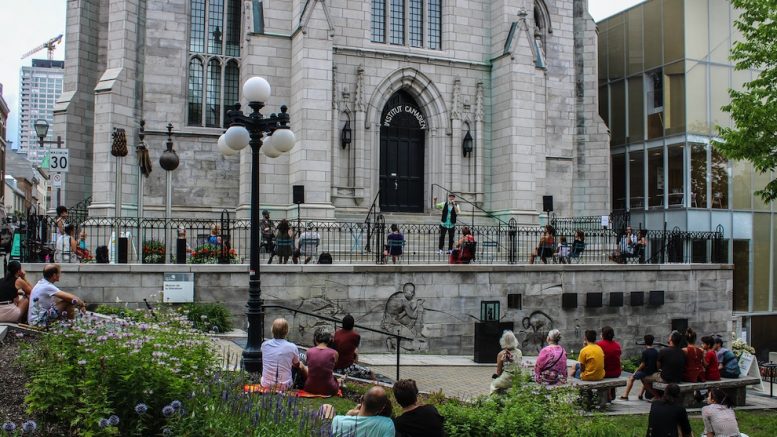Des citoyens qui écoutent un conteur sur le parvis de la Maison de la littérature